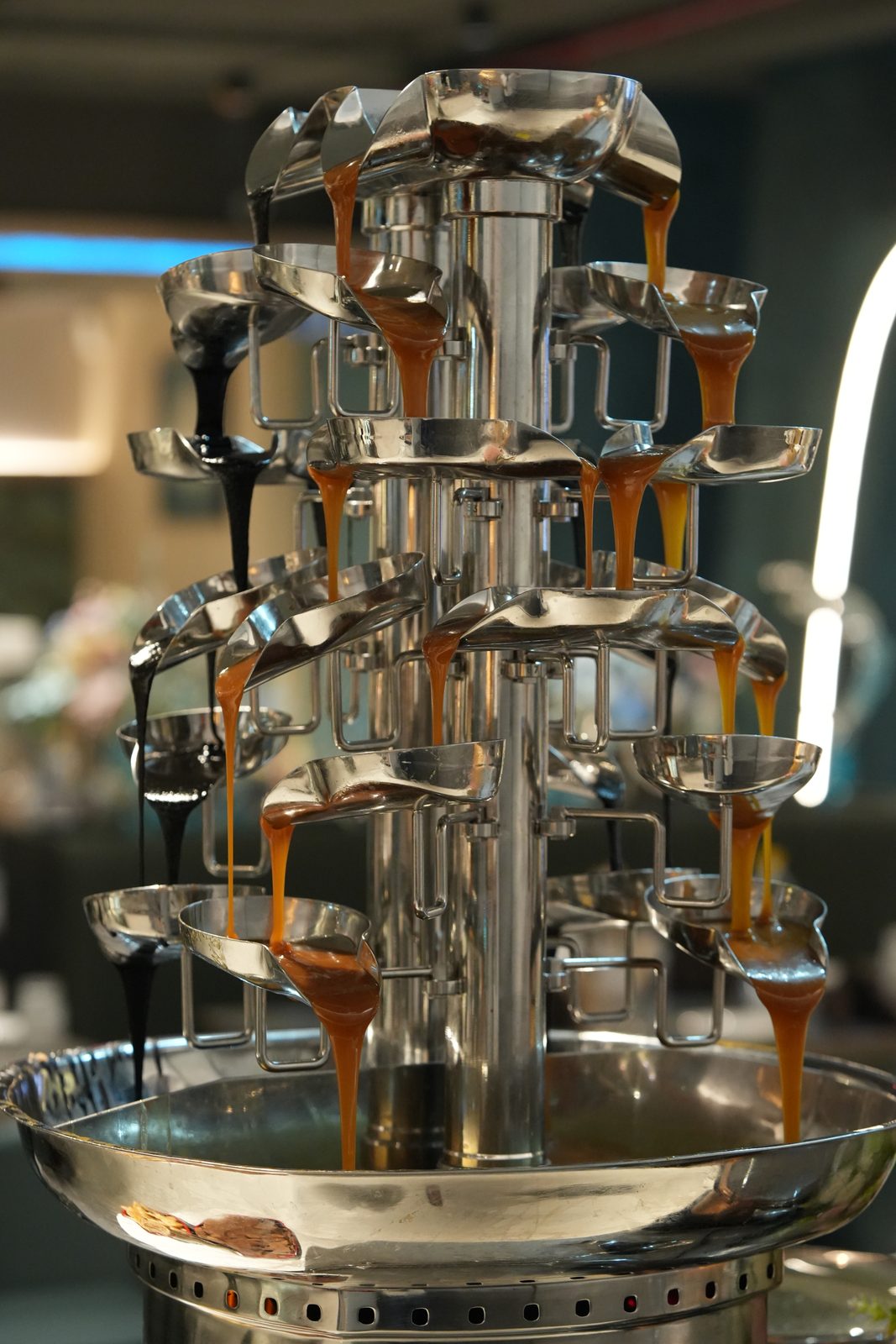 The chocolate fountain with melted chocolate flowing over its tiers