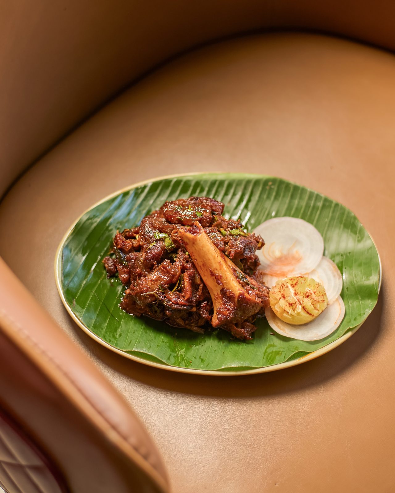 Mutton on the bone served on banana leaf with sliced egg